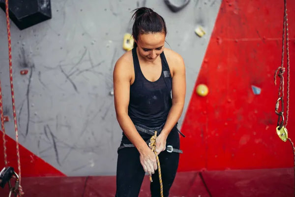 Kadın tırmanıcı düğümle ip bağlayıp tırmanmaya hazırlanıyor. Tırmanma ekipmanı — Stok fotoğraf