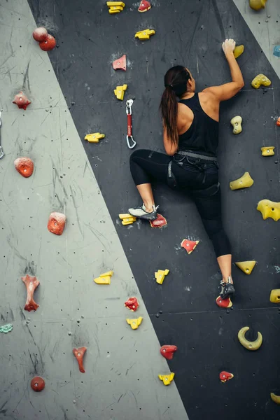 Mulher praticando escalada na parede artificial dentro de casa. Estilo de vida ativo e conceito de pedregulho. — Fotografia de Stock