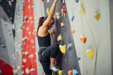 Renkli bir tırmanış salonunda spor yapan genç bir kadın..