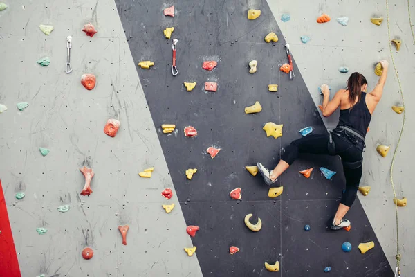 Sportieve jonge vrouw training in een kleurrijke klimzaal. — Stockfoto