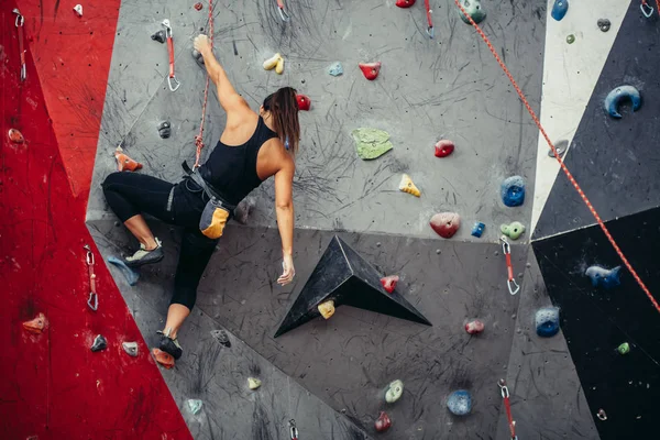 Treinamento esportivo jovem em um ginásio de escalada colorido. livre alpinista menina escalando até interior — Fotografia de Stock