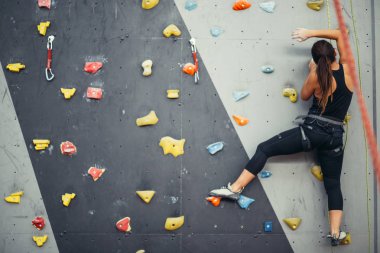 Renkli bir tırmanış salonunda spor yapan genç bir kadın..