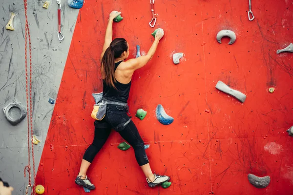 Belle jeune femme faisant un grand pas vers le haut d'un mur artificiel — Photo