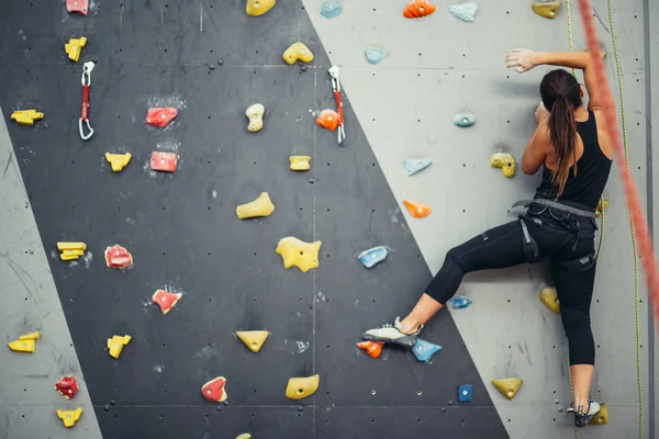 Renkli bir tırmanış salonunda spor yapan genç bir kadın..