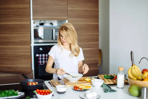 Mujer mezclando deliciosos ingredientes de ensalada de superalimentos con cucharas de madera en la cocina — Foto de Stock