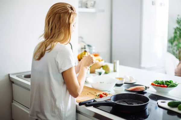 Jovem dona de casa fazendo refeição para linch na cozinha. vista traseira — Fotografia de Stock