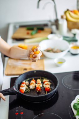 Genç ve mutlu ev kadınının akşam yemeği için tavuk eti kızartışı görüntüsü.