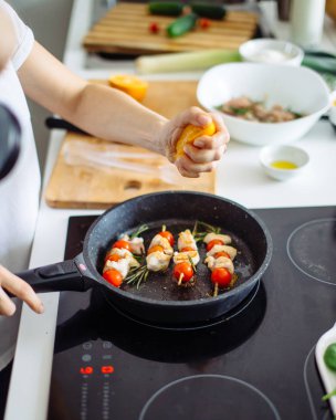 Kadın kırpılmış görünümünü soba kızartma üzerinde Marine edilmiş tavuk kebap üzerine dökerek portakal suyu eller. Sağlıklı gıda hazırlama. Diyet kavramı. Sağlıklı bir yaşam tarzı. Evde yemek. Yemek hazırlamak