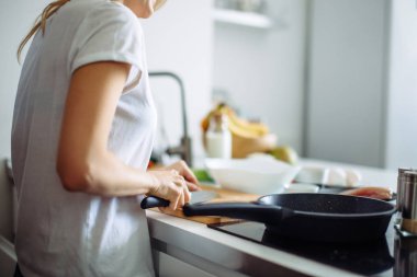 Genç bayan aşçı mutfakta yemek pişiriyor.