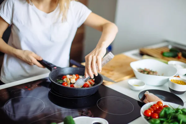 Cropped view of young happy housewife frying chicken meat for dinner — Stock Photo, Image