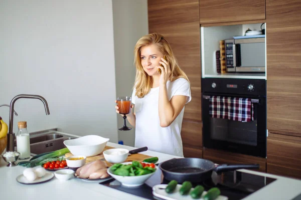 Mujer haciendo comida saludable y leyendo el mensaje en el teléfono en la cocina doméstica. — Foto de Stock