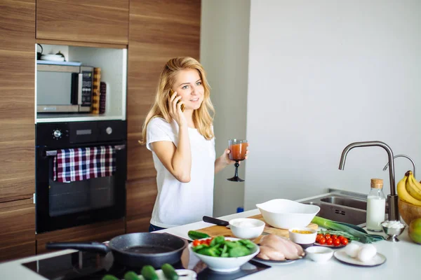 Donna che prepara pasti sani e legge messaggi al telefono nella cucina domestica. — Foto Stock