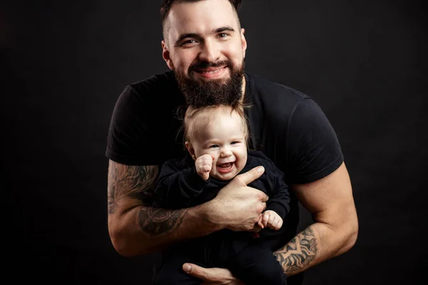 Young athletic father with adorable baby on black background — Stock Photo, Image