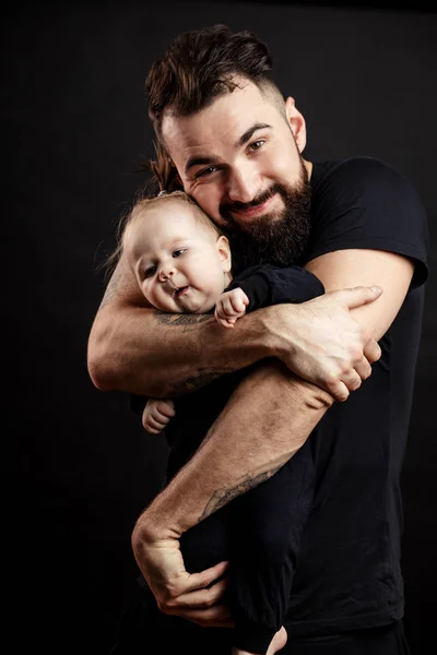 Joven padre atlético con adorable bebé sobre fondo negro —  Fotos de Stock