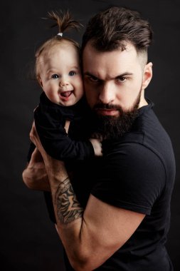 Şirin bebek siyah arka plan üzerine tutarak dövmeli yakışıklı genç