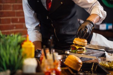 Şef sığır eti, salata ve sebzeli bir burger hazırlar..