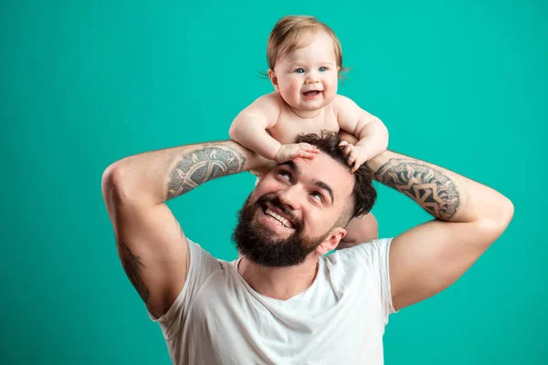 Pai feliz carregando sua filha bebê no pescoço isolado sobre fundo azul — Fotografia de Stock