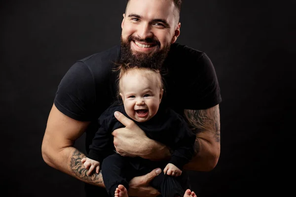 Jonge atletische vader met schattige baby op zwarte achtergrond — Stockfoto