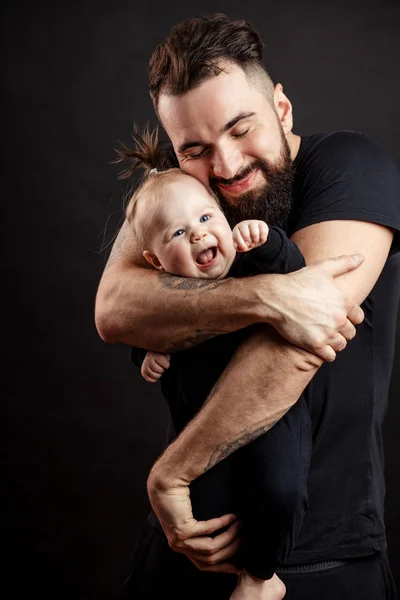 Jovem pai atlético com bebê adorável no fundo preto — Fotografia de Stock