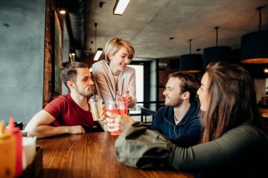 Mutlu arkadaşlar içecekler içerken kafede birlikte vakit geçirirken eğleniyorlar.