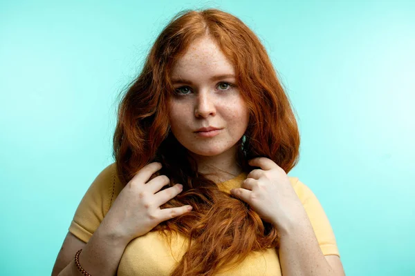 Menina ruiva com cabelo encaracolado cruzado sorrindo olhando para a câmera sobre fundo azul — Fotografia de Stock