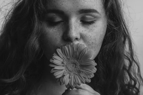 Primer plano de hermosa mujer pelirroja oliendo flor sobre fondo amarillo — Foto de Stock