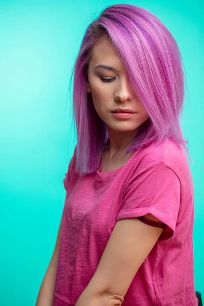 Attraente ragazza con i capelli rosa, vestita in tessuto rosa casual su sfondo blu . — Foto Stock