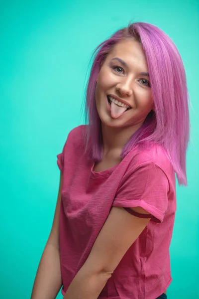 Menina estudante engraçado com cabelo pinl se divertindo ao mostrar a língua . — Fotografia de Stock