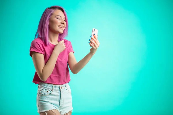 Mujer sonriente haciendo foto selfie en el teléfono inteligente aislado sobre un fondo azul — Foto de Stock