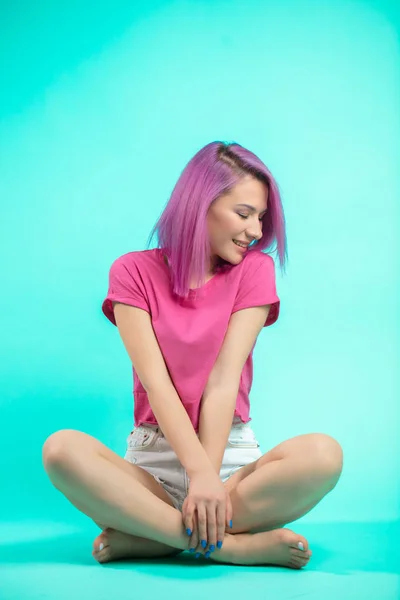 Estudante sentado no estúdio. Menina com cabelo rosa reto sentado no chão . — Fotografia de Stock