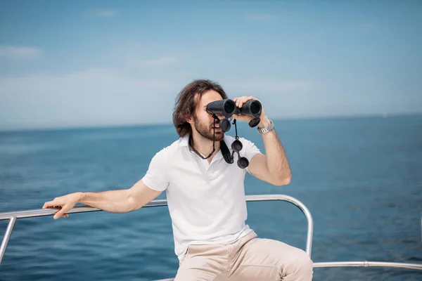 Man looks through binoculars from the boat