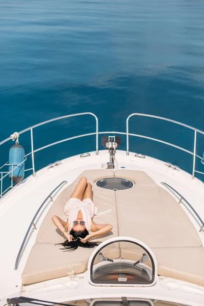 요트를 타고 일광욕을 즐기며 범선 갑판에 앉아 있는 매력적 인 여자 — 스톡 사진