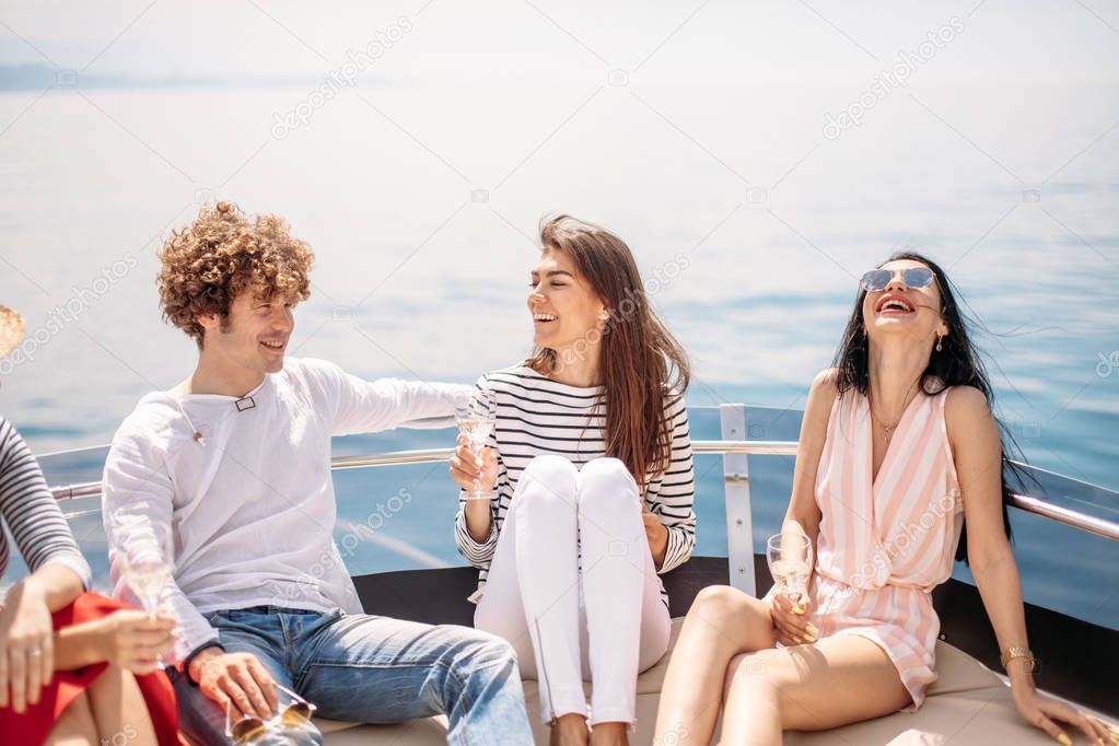 Friends having fun sailing on a yacht in sea, laughing, chatting and chilling