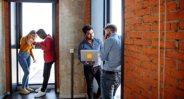 Joven hombre de negocios confiado usando un teléfono inteligente parado en la ventana de la oficina — Foto de Stock