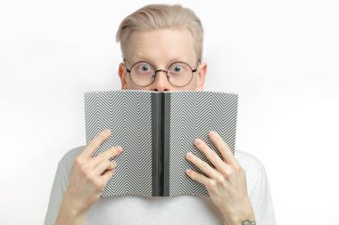 Şaşırmış sarışın adam beyaz arka planda açık gri ile ağzını kapatıyor.