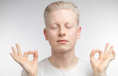 Yoga yapan, gözlerini kapayan konsantre sarışın bir adam..