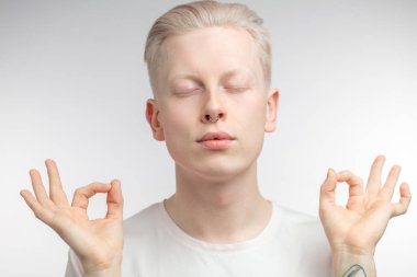 Yoga yapan, gözlerini kapayan konsantre sarışın bir adam..