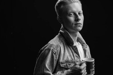 Kot jaket giyen yakışıklı sarışın Amerikalı adam siyah arka planda izole edilmiş.