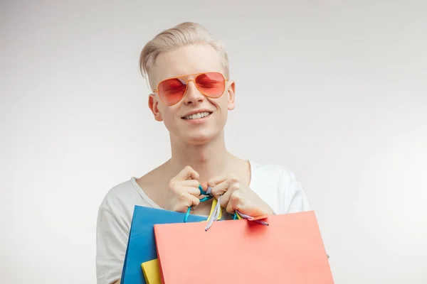 Portret van mode jongeman in roze bril met boodschappentassen — Stockfoto