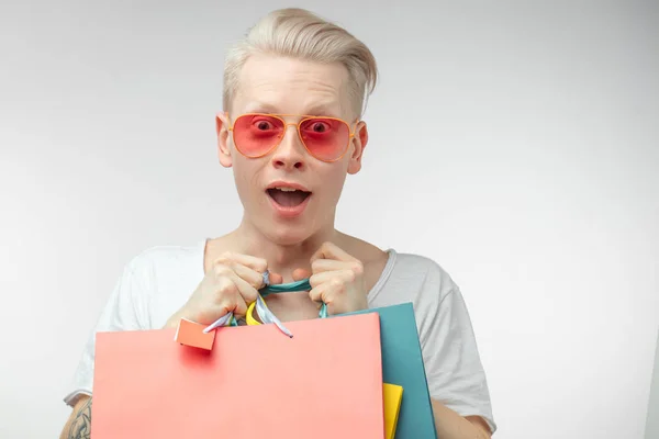 Porträtt av mode ung man i rosa glasögon med shoppingväskor — Stockfoto