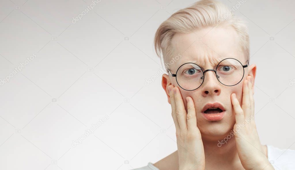 Blonde shocked man with wide opened mouth and bugged eyes shouting with horror.