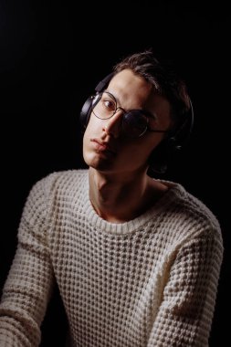 Beyaz tişört ve güneş gözlüğü takan yakışıklı bir erkek mankenin stüdyo fotoğrafı.