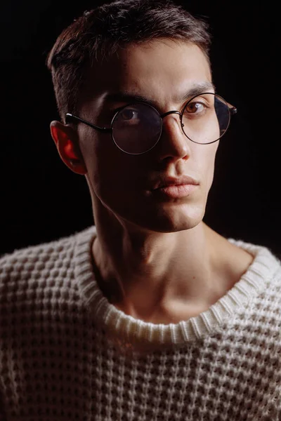 Studio shot of a handsome young male model wearing white sweater and sunglasses