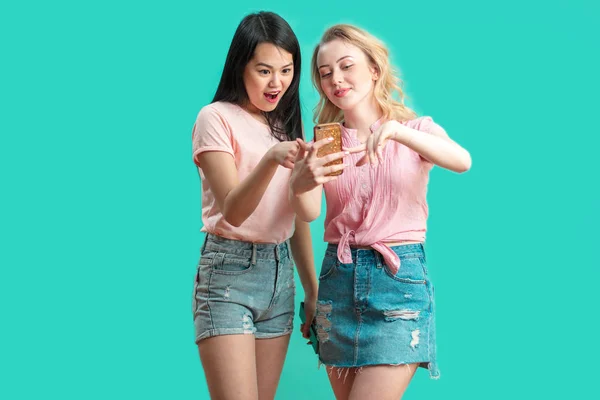 Dos multiétnicas hermosas mujeres asiáticas y caucásicas tomando selfie en estudio — Foto de Stock