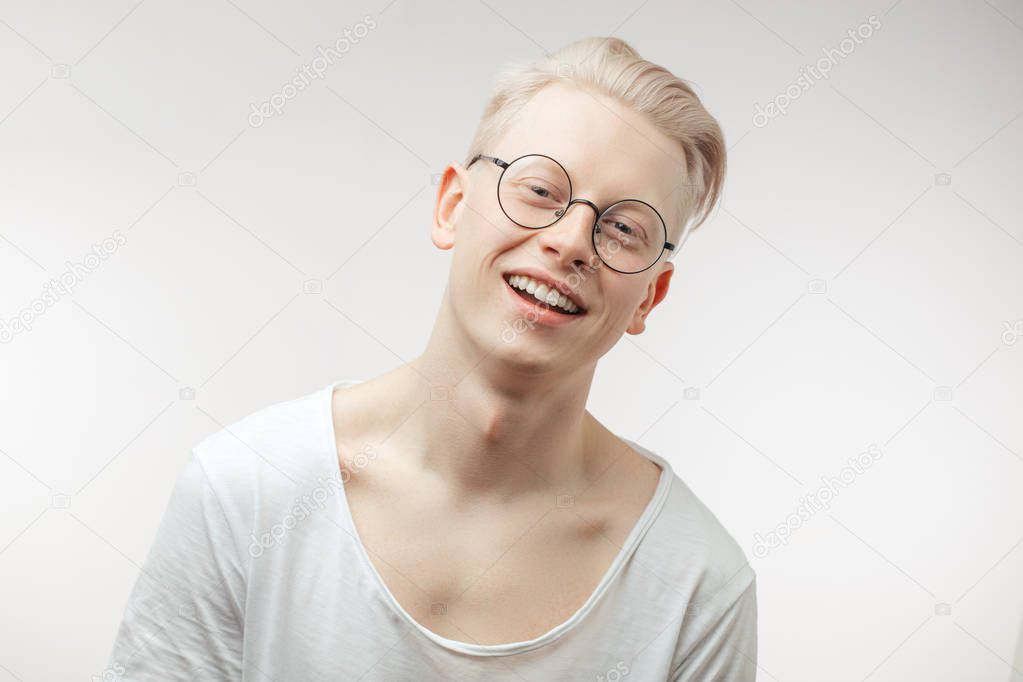 Hipster guy with blond hair smiling having cheerful look. Positive emotions