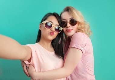 Farklı kızlar günlük kıyafetlerle çekim yapıyor. Mavi arka planda izole edilmiş selfie çekiyorlar..
