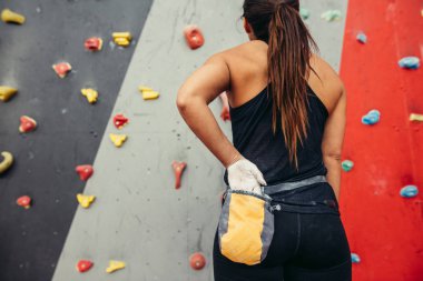 Dikiz manzaralı dağcı kadın, belindeki torbadan çıkan tebeşir tozuyla ellerini ovuşturuyor..