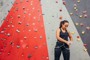Dağcı uygun koşum takımı kapalı kayalıklarda tırmanmaya hazırlanıyor.