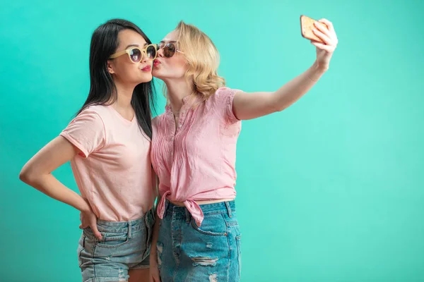 Diverse meisjes in casual outfits schieten selfie geïsoleerd op blauwe achtergrond. — Stockfoto
