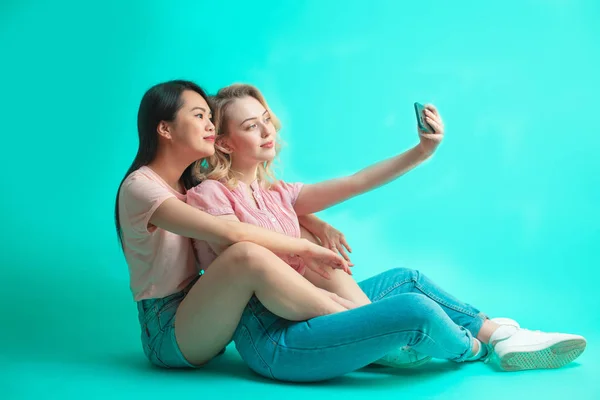 Portret dwóch radosnych kobiet robiących sobie selfie siedząc na podłodze — Zdjęcie stockowe